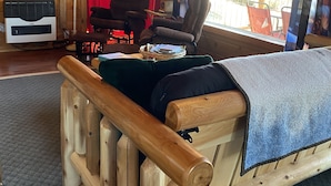 A wooden cabin interior with a bed, chairs, a television, and a window with curtains. - Wilderness Spirit Cabins, LLC-'Eagle Nest'- Heavenly Mountain Views (Corvallis)