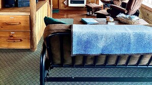A wooden cabin interior with a staircase, a television, a fireplace, and a large window. - Wilderness Spirit Cabins, LLC-'Eagle Nest'- Heavenly Mountain Views (Corvallis)