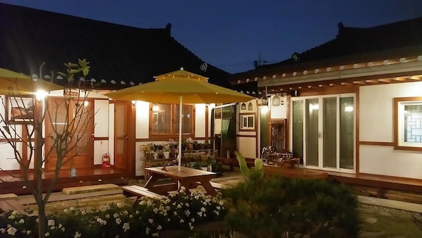 A traditional Japanese-style building with a covered patio area, wooden furniture, and potted plants. - Hanok Raon (Gyeongju)