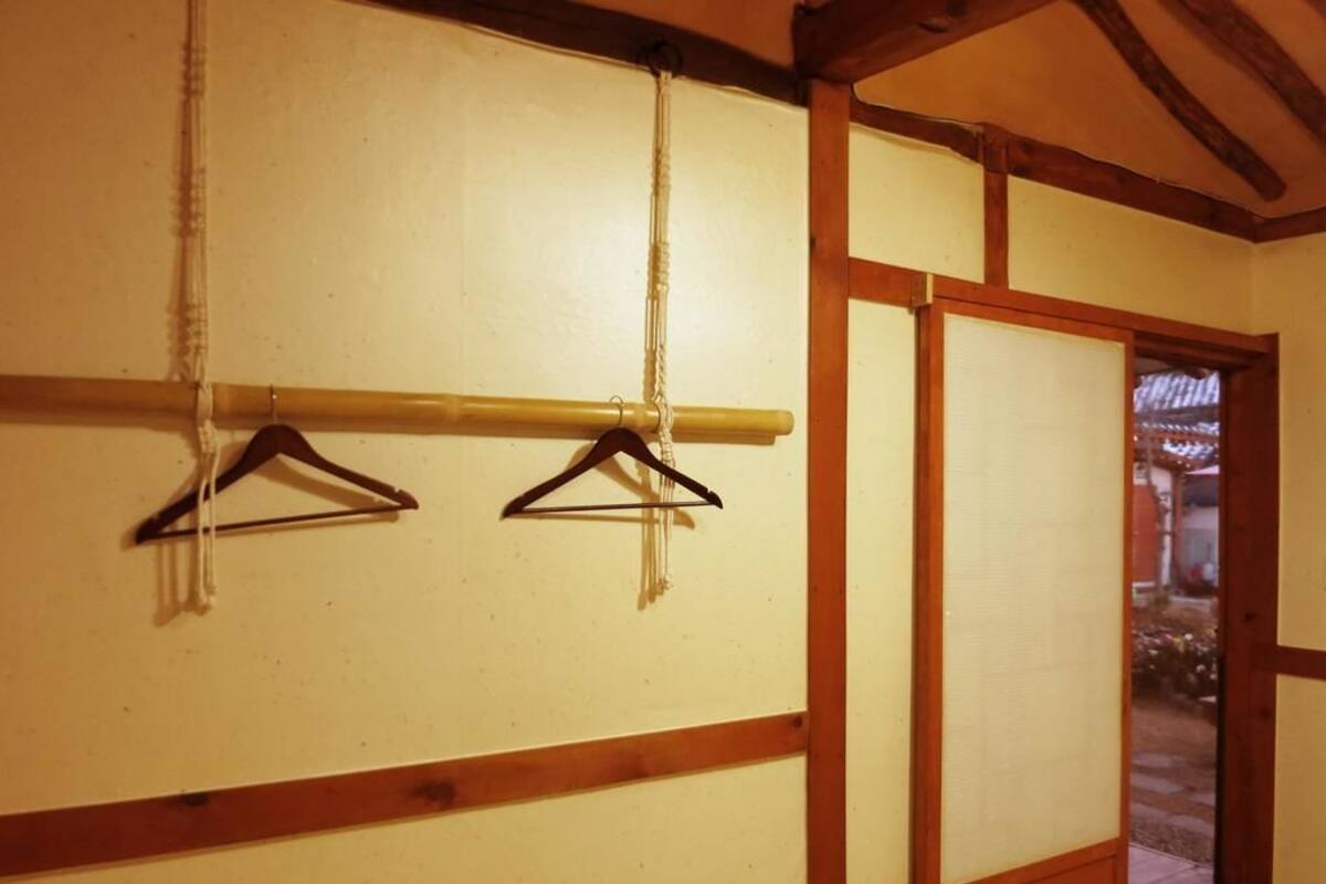 A traditional Japanese room with wooden beams, tatami flooring, and a sliding door leading to an outdoor area.