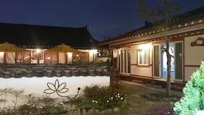 A traditional Japanese-style building with a tiled roof, a courtyard with a stone pathway, and a large flower design on the wall. - Hanok Raon (Gyeongju)