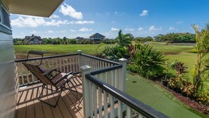 A deck with a view of a golf course and houses.