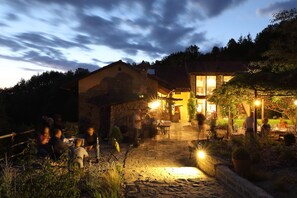 En bygning i sten med et stort glasvindue og en patio med borde og stole.
