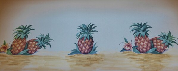 A painting of pineapples with leaves and a flower on a wooden surface.