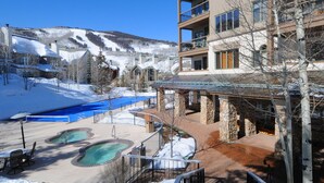 Un complexe hôtelier doté d'une piscine, de bâtiments en pierre et offrant une vue sur des montagnes enneigées.