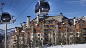 Une station de ski dotée de télécabines, de bâtiments en bois et d’un paysage enneigé.