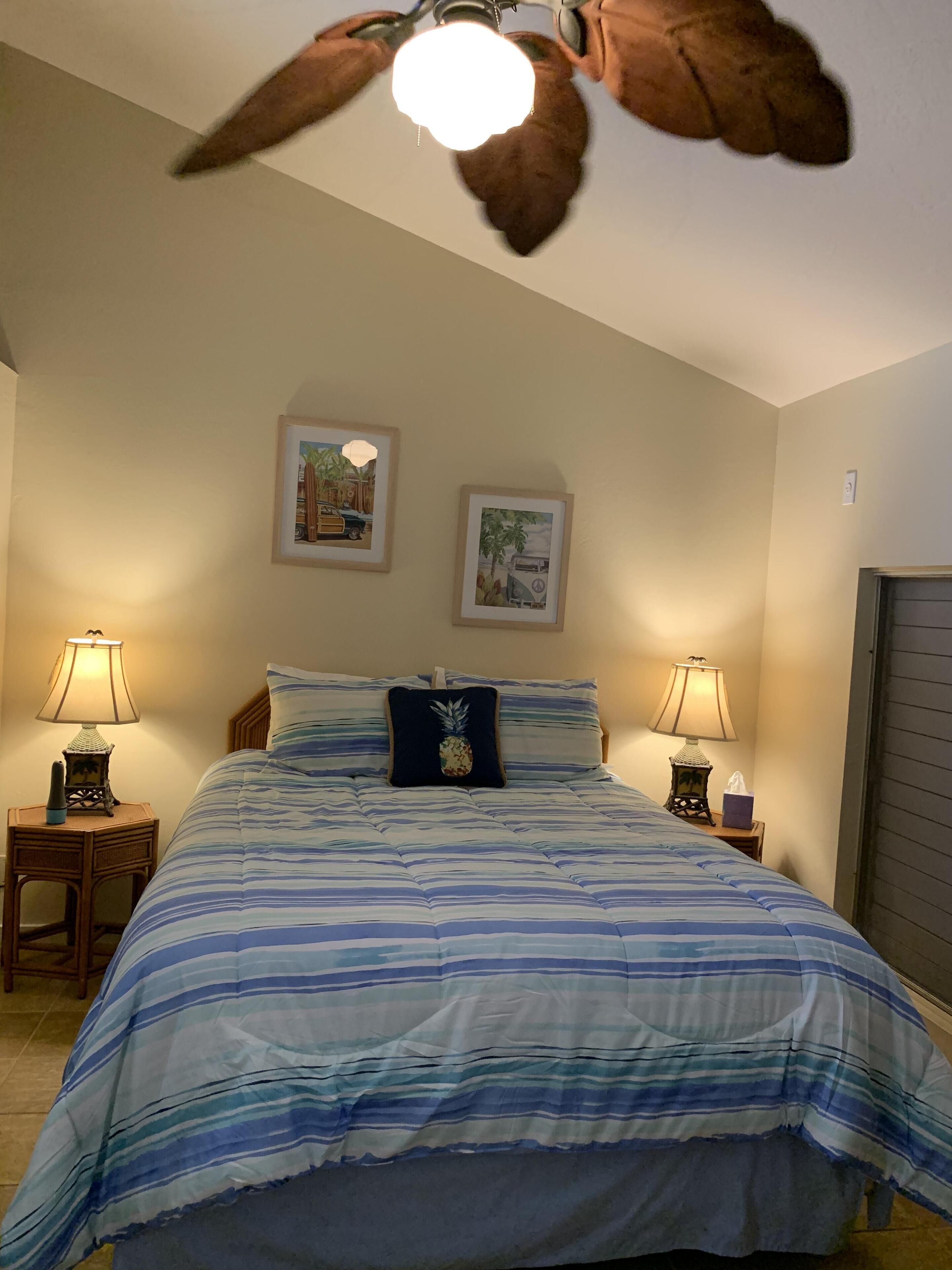 Un dormitorio con una cama, dos lámparas de pared y dos cuadros enmarcados.