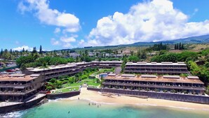 Un resort con varias edificaciones, una playa y montañas al fondo.