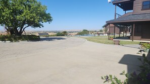 Un camino de entrada residencial con un árbol, un porche cubierto y vistas a una piscina y un paisaje lejano.