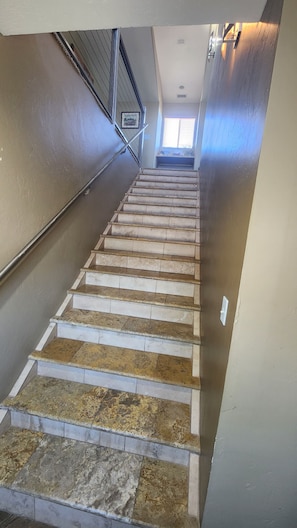 Stairs lead upwards, flanked by painted walls and a metal handrail.