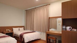 Una habitación de hotel con dos camas, un escritorio, una silla, un espejo y un armario.