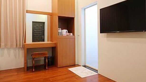 Habitación compacta con piso de madera, un escritorio empotrado con silla, televisor de pantalla plana en la pared y unidad de aire acondicionado.