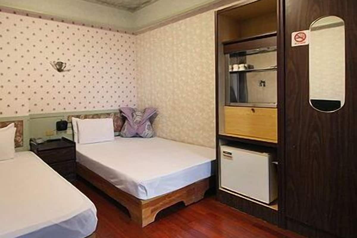 A room with two beds, a small cabinet, and a mirror on the door.
