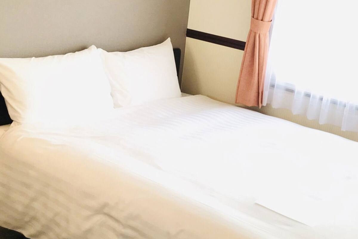 A neatly made bed with white linens in a hotel room.