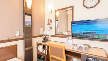 A hotel room with a bed, desk, chair, and a television displaying a scenic view.