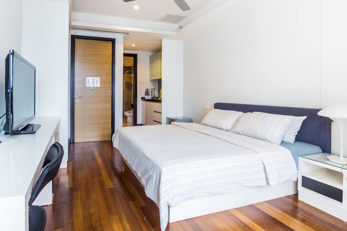 Une chambre d’hôtel moderne avec un grand lit, un bureau équipé d’un ordinateur et une télévision.