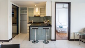 Una cocina moderna con una isla central, un refrigerador y una zona de comedor con dos taburetes de bar.