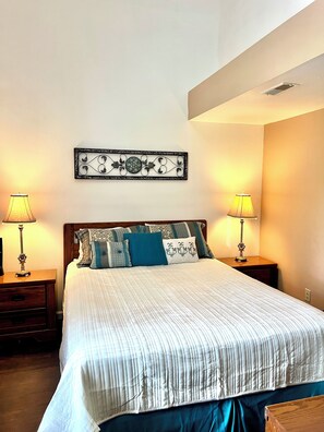A neatly made bed with a striped bedspread, two bedside lamps, and a decorative wall piece above the bed. - Roomy & fresh condo, quiet scenic area, close to strip, lakes & Branson fun. (Branson)