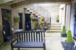 Un patio con un banco, una escalera en espiral y plantas en macetas.