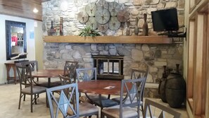 Cozy dining area with a wooden table and six chairs, a flat-screen TV, and a fireplace.