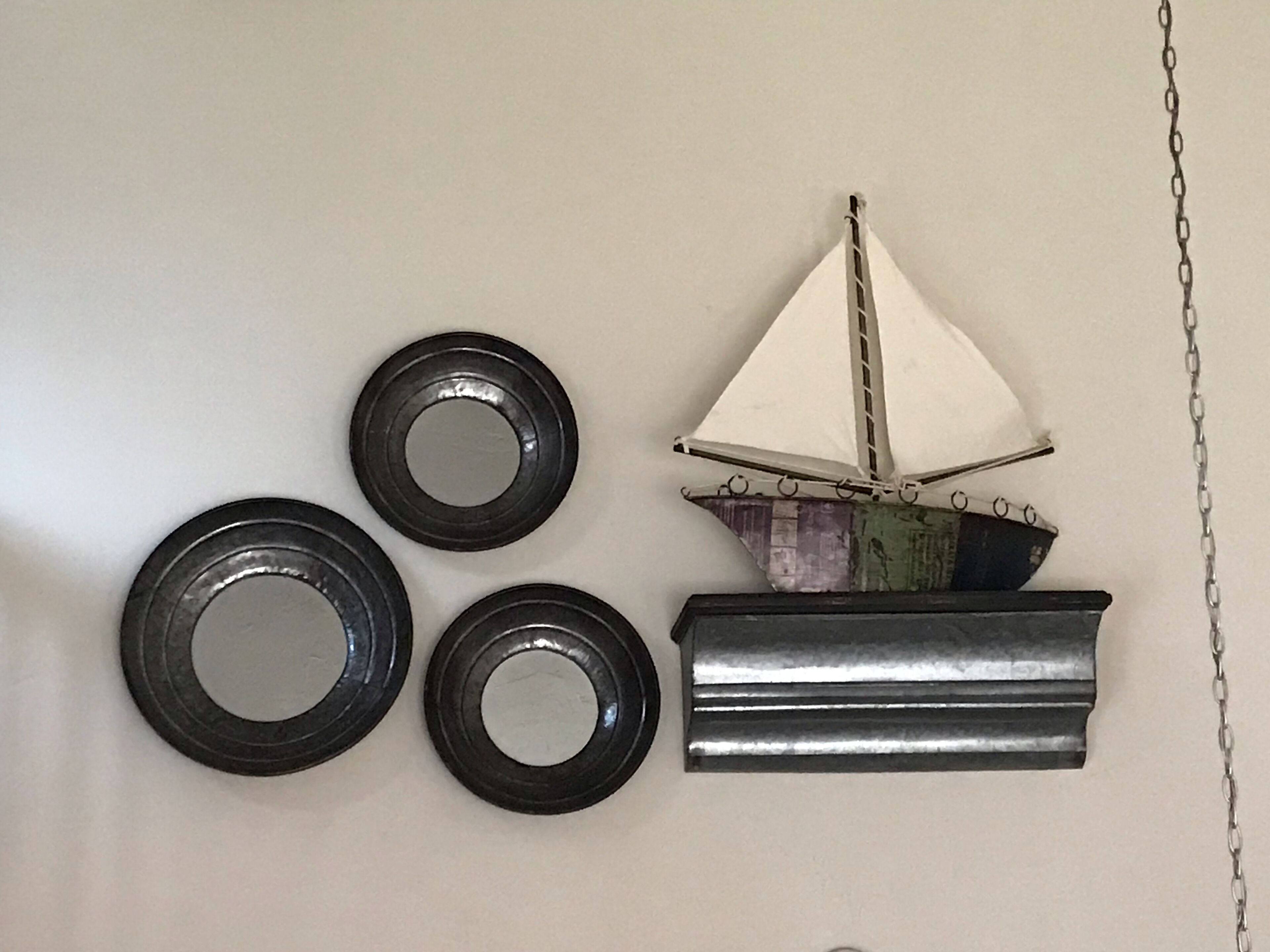 Una pared decorada con un velero y cuatro objetos circulares.