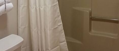 Une salle de bain comprenant des toilettes, un espace douche et une baignoire.