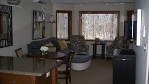 Ein Wohnzimmer mit einer Couch, Sesseln, einem Esstisch und einem Fernseher.
