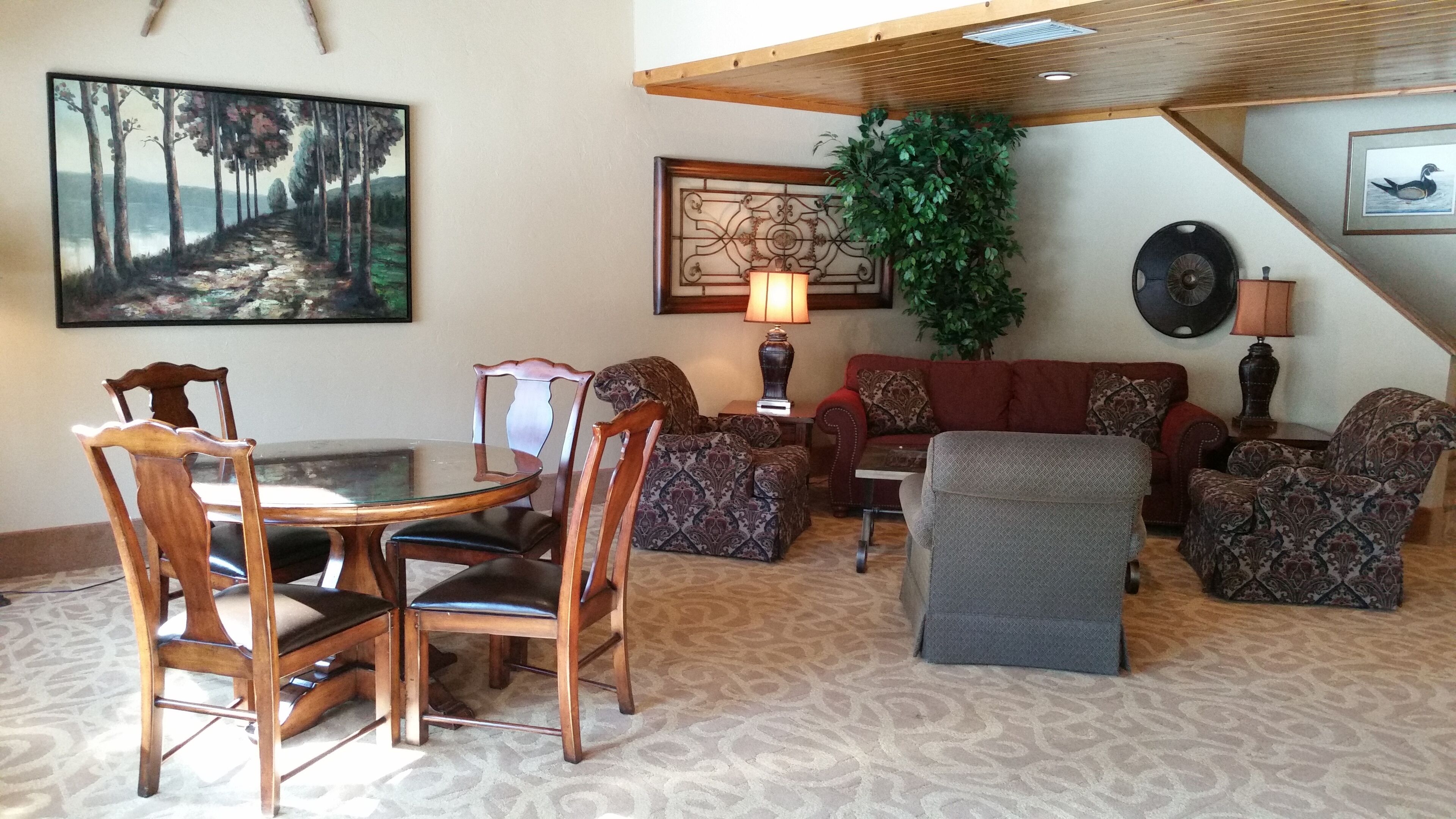 A living room with a dining table, chairs, a sofa, and a patterned carpet.