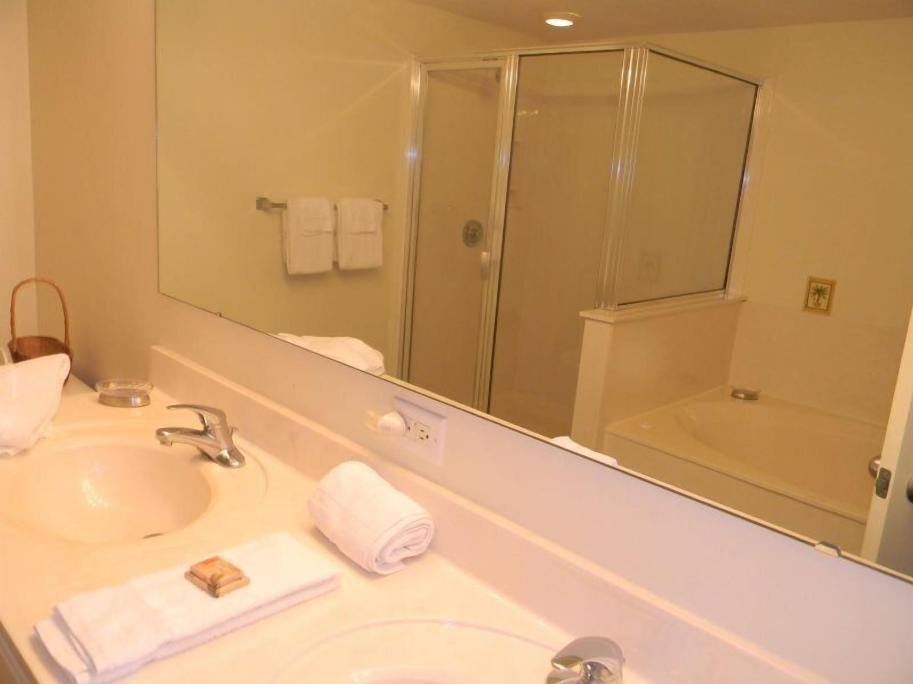 A bathroom with a sink, mirror, and glass shower enclosure.