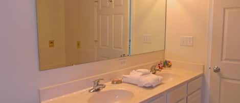 A bathroom with a large mirror, two sinks, and a door.