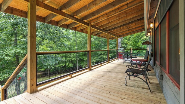 A wooden deck with a railing overlooking a forested area.