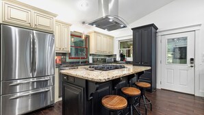 A modern kitchen with stainless steel appliances, a large island with stools, and dark cabinetry.