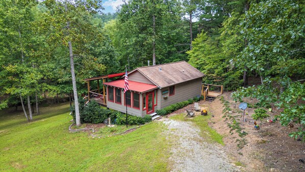 A cabin with a red roof, a deck, and a small porch.