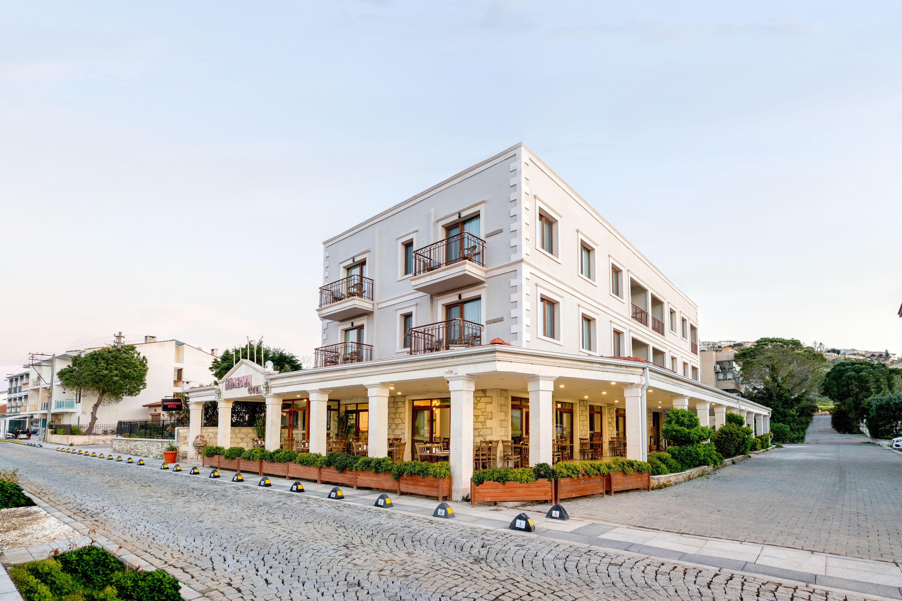 A multi-story hotel with a white facade, balconies, and a covered outdoor seating area.