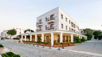A multi-story hotel with a white facade, balconies, and a covered outdoor seating area.