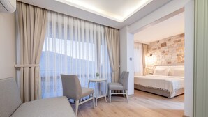 Una habitación de hotel con una cama, dos sillas, una mesita y una pared de piedra.