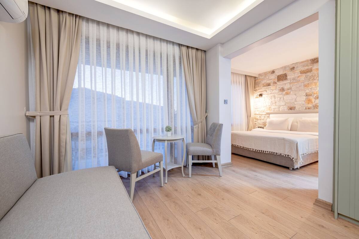 Ein Hotelzimmer mit einem Bett, zwei Stühlen, einem kleinen Tisch und einer Steinwand.