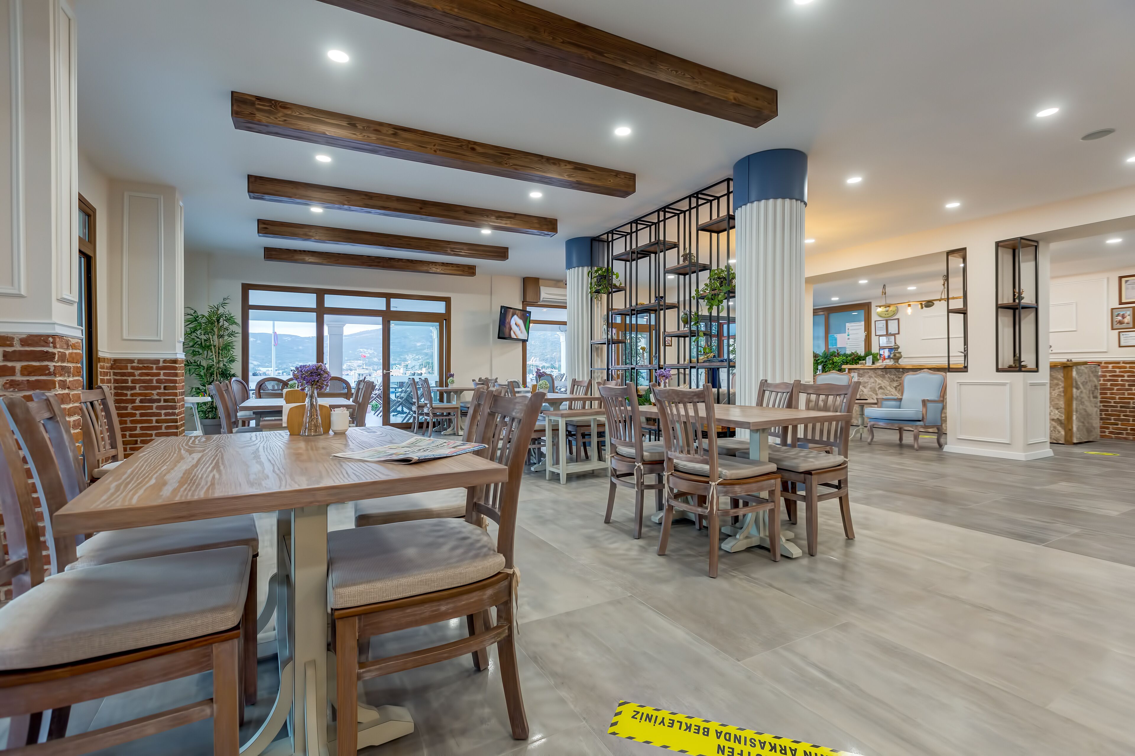 Un comedor amplio con mesas y sillas de madera, un muro de acento de ladrillo y vistas a la ciudad.
