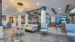 Un vestíbulo amplio con techo alto, muebles modernos y un mueble central con plantas.