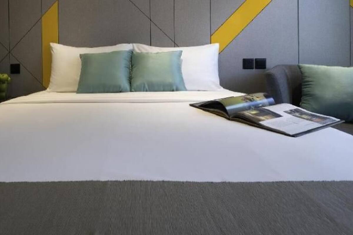 A bed with pillows, a magazine, and a vase of flowers.