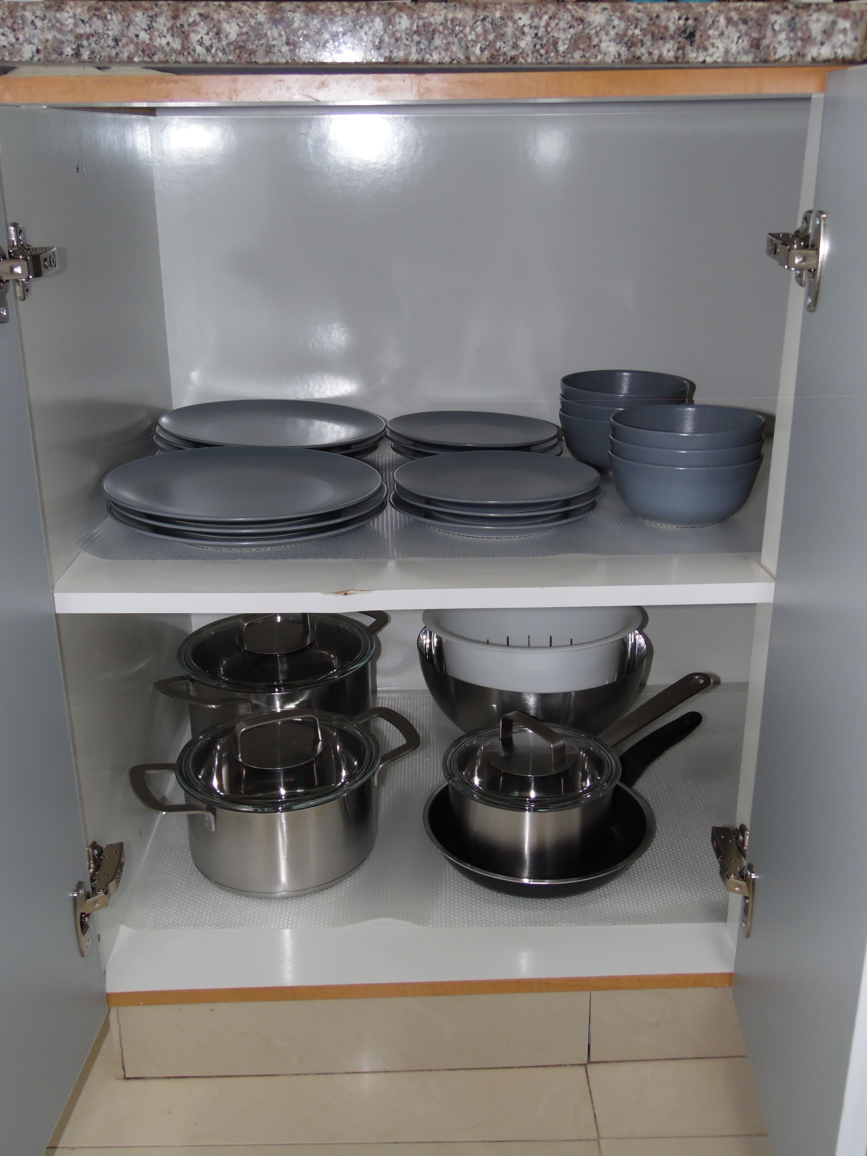 Un mueble de cocina con utensilios de cocina de acero inoxidable y tapas negras.