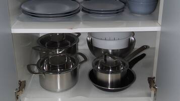 Un mueble de cocina con utensilios de cocina de acero inoxidable y tapas negras.