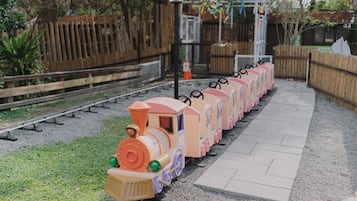 Explore a charming miniature train set on a scenic track, surrounded by lush greenery and a picturesque fence.
