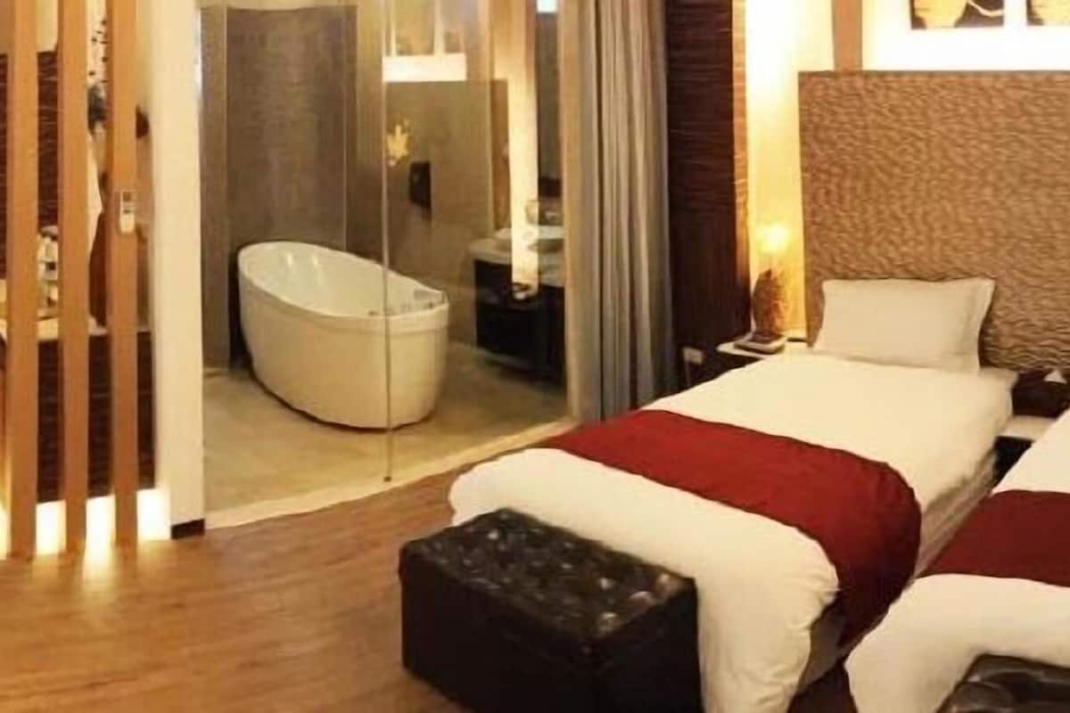 A hotel room with two beds, a bathroom, and a small seating area.