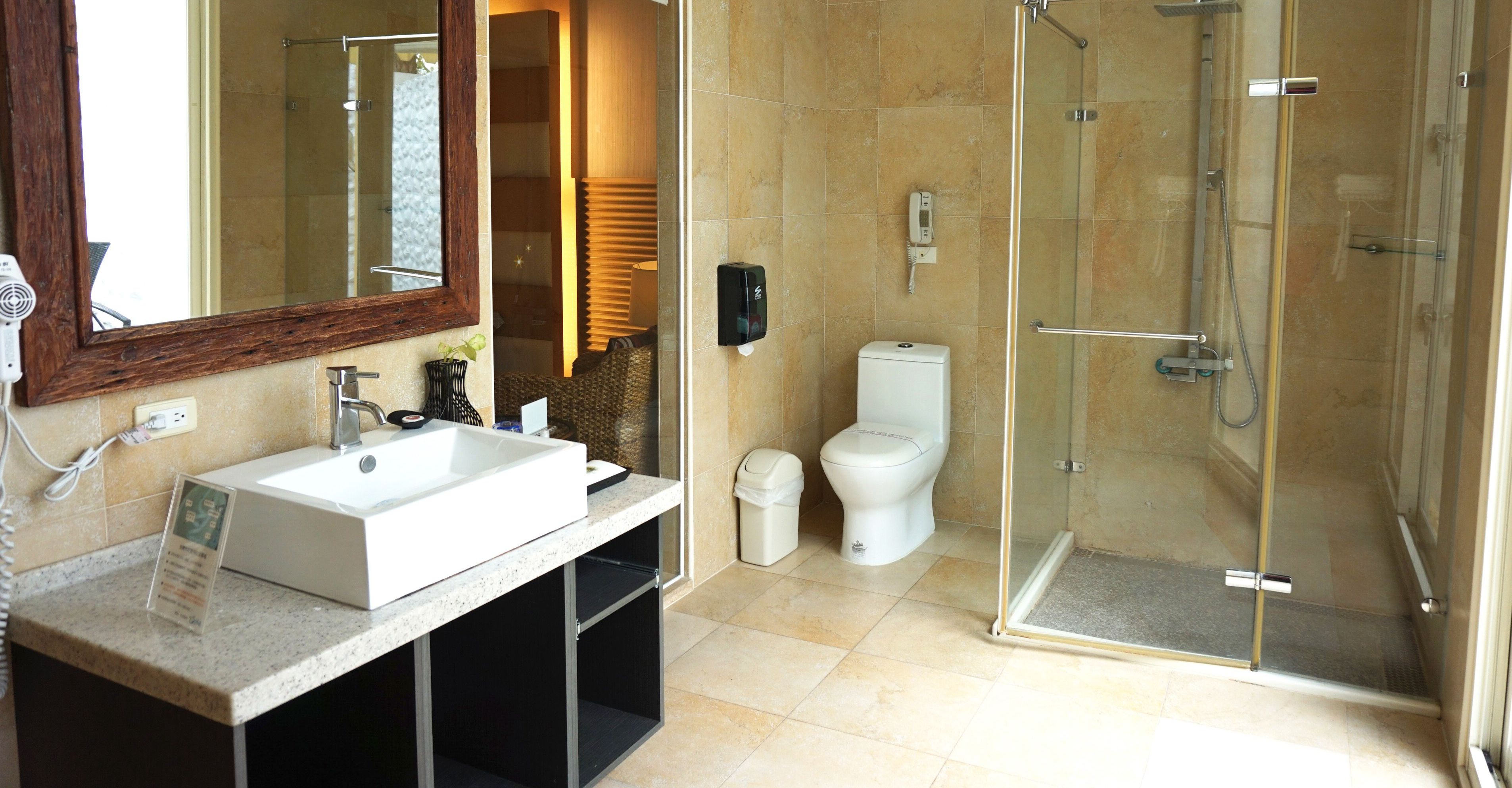 A modern bathroom with a large mirror, a sink, a toilet, and a glass-enclosed shower.