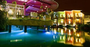 Een hotel met meerdere verdiepingen, een zwembadgedeelte, terrasmeubels buiten en een overdekt terras.