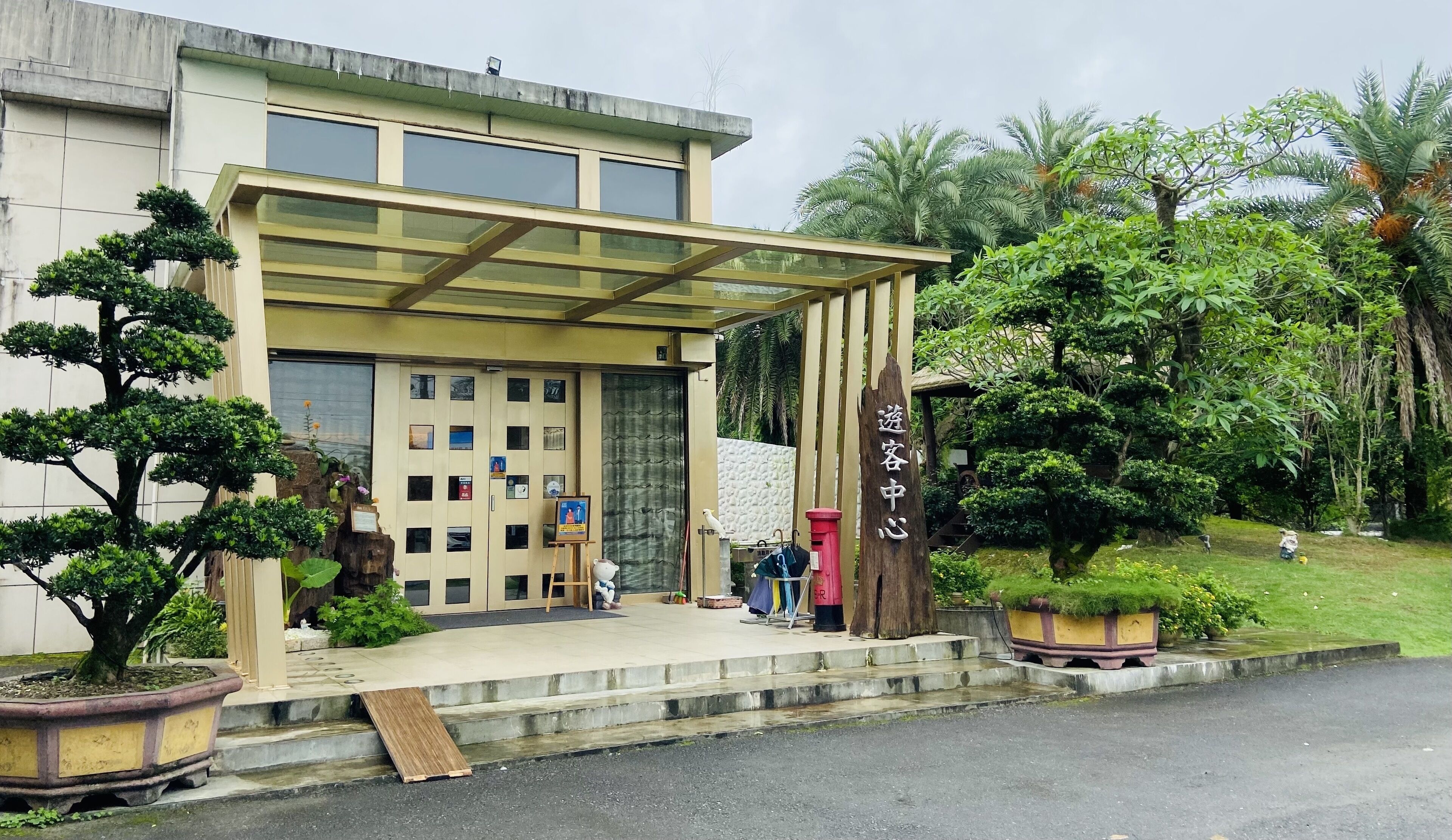 A building with a glass entrance, a covered waiting area, and a sign reading "Guest Center".