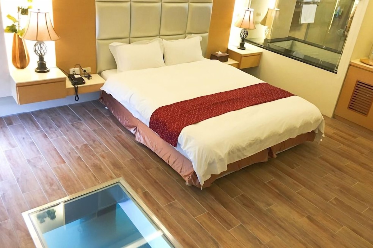 Une chambre d’hôtel avec un lit, des tables de chevet, des lampes, un miroir et une fenêtre.