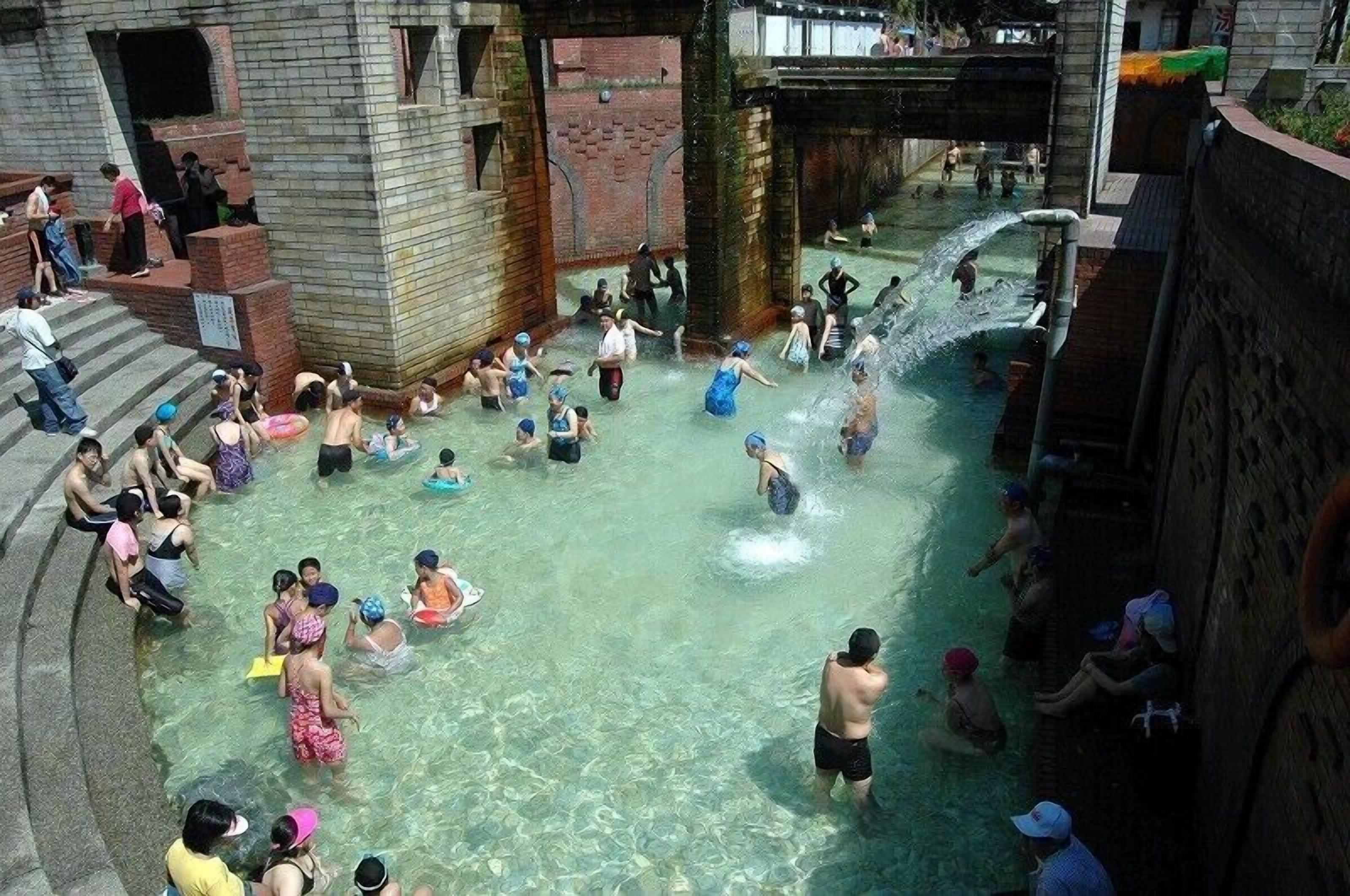A public bath area with multiple water features and people enjoying the facilities.