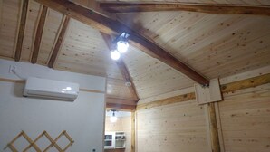 Una habitación con vigas de madera en el techo, un equipo de aire acondicionado en la pared y una ventana con vistas.